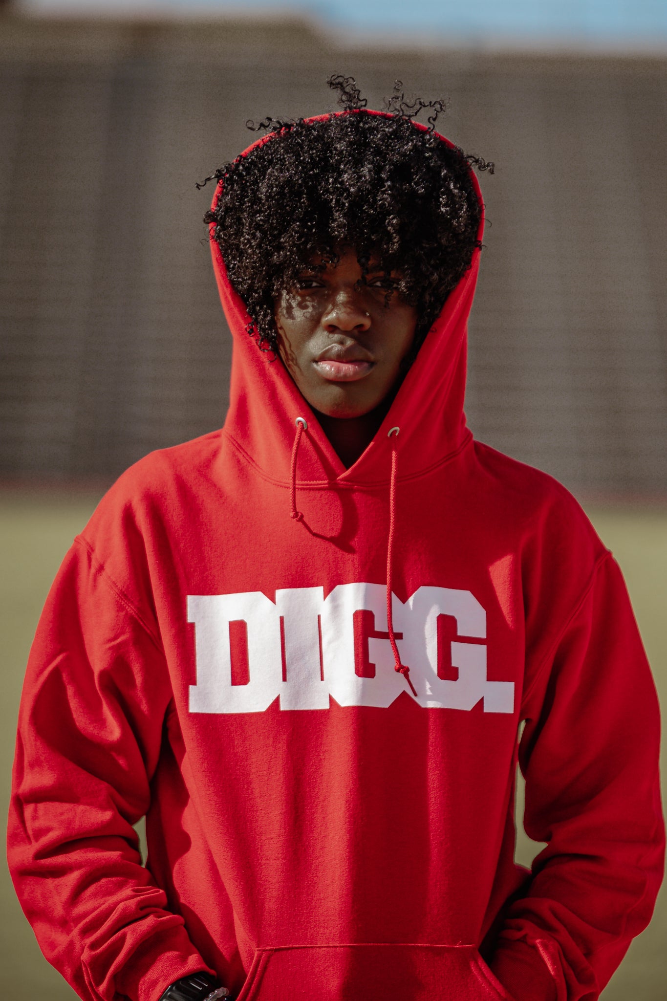 Jaiya Devi wearing a red hoodie with 'Digg' printed on it against a blurred background